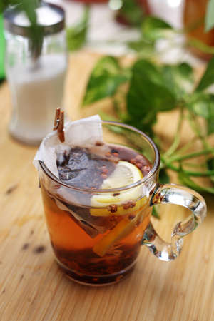 Cup of fruit tea with lemon on a wooden table, top view. Hot healthy herbal drink. Making a tea with a tea bag.の写真素材