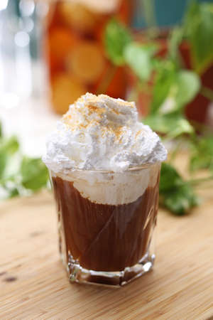 Hot chocolate drink with whipped cream and cinnamon in a glass on a wooden table, vertical view. A shake, iced coffee, photo with selective focus and blurred background.の写真素材
