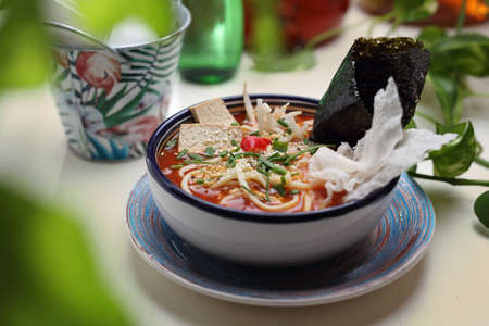 Bowl of Korean, oriental tomato soup. Kimchi soup with tofu, Japanese noodles and spices. Vegan food.の写真素材