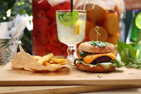Vegan lunch set. Vege burger, potato fries and lemonade on a wooden cutting board. Plant-based meal, horizontal view.の写真素材