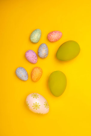 Hand painted easter eggs on a yellow background, top view. Easter decorations, postcard, photo with a copy space.の写真素材