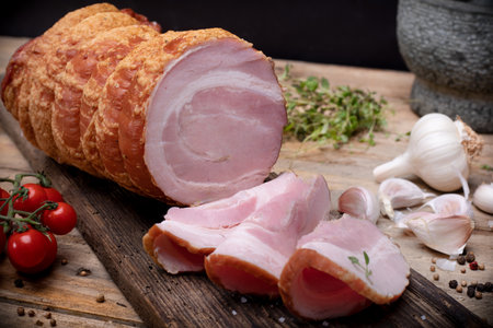 Smoked rolled bacon, roulade, rolled pancetta on wooden boards. Rustic composition with Polish cold cuts, meat products.の写真素材