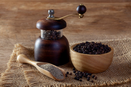 Black pepper and pepper grinder on wooden floorの写真素材