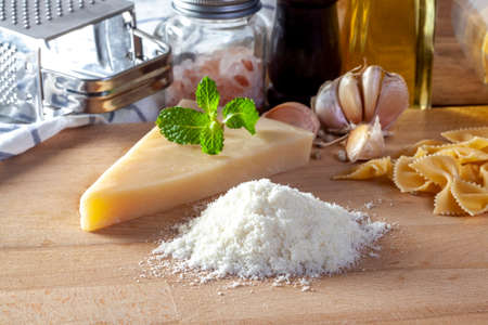Grated parmesan cheese and metal grater on wooden boardの写真素材