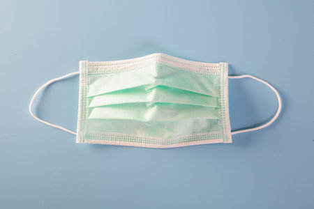 Mask with rubber ear straps. Typical 3-ply surgical mask to cover the mouth and nose. Procedure mask...