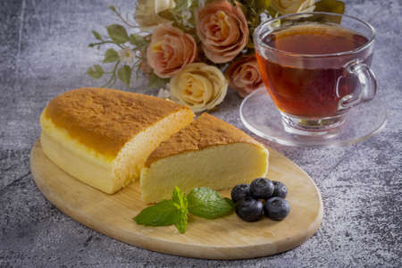 Wooden desk with Japanese cheesecake and afternoon tea, Close up.の写真素材
