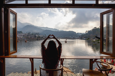 Asian woman making heart shape hands look at the sunrise in the morning Watch the fog and river view. Chinese Settlement Lee Wine Ruk Thai Mae Hong Son, Thailandの写真素材