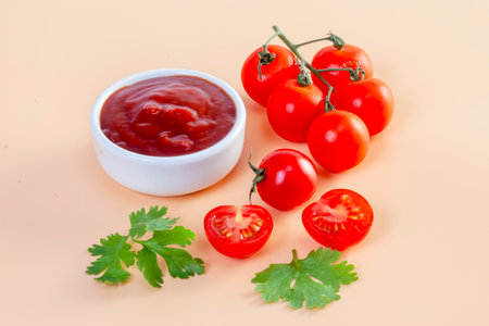 Freshly prepared ketchup with ripe red tomatoes on orange backgroundの写真素材