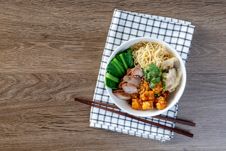 Egg noodle with red roast pork, crispy pork, dumplings, soup and condimentsの写真素材