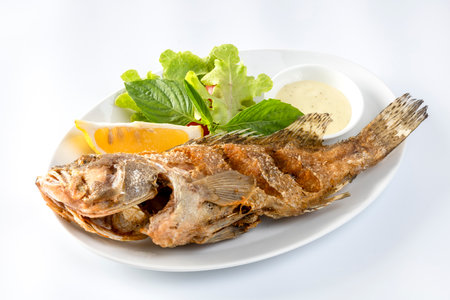 Fried sea bass Fried until golden crisp, in a white dish,  on a table.の写真素材
