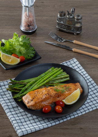 Grilled Salmon with Asparagus, Tomatoes and Lemon on Black Plateの写真素材