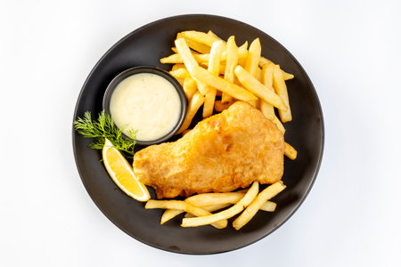 fish and chips served with french fries and tartar sauce with sliced lemon on plate isolated on white background.の写真素材