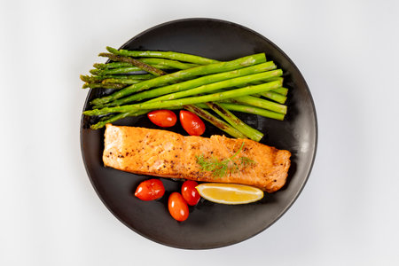 Grilled Salmon with Asparagus, Tomatoes and Lemon on Black Plateの写真素材