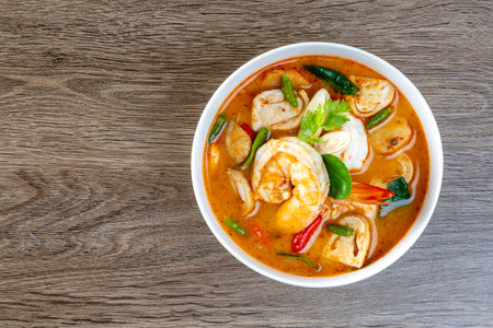 Prawn Tom Yum in a white bowl on a wooden table
