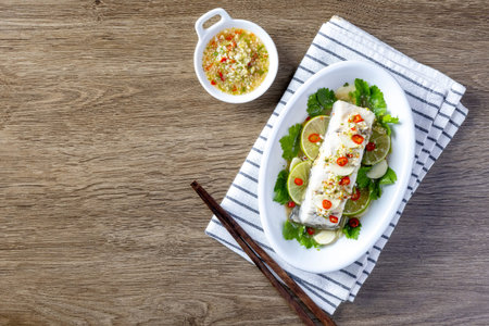 Steamed sea bass with lemon sauce served on a wooden table.の写真素材
