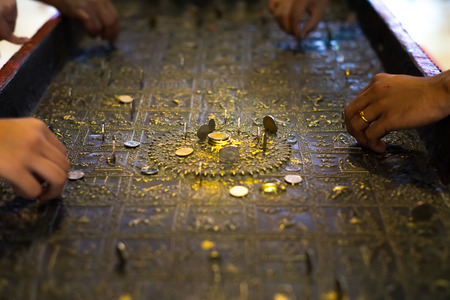 People try to put coin on Buddha's footprint statute.の写真素材