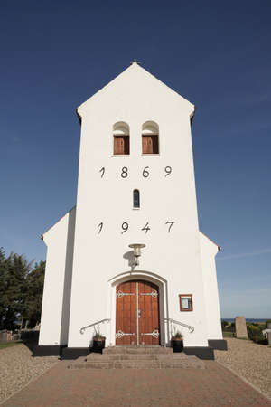 Haurvig Kirke and its cemetery with sea in background and blue skyの写真素材