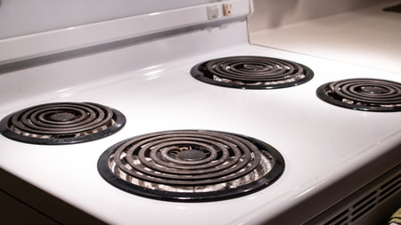 Stovetop burners on an old-fashioned gas white stove, dimly lit, Toronto, Canada.