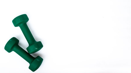 A pair of green dumbbells on a white background, isolated, lots of space for copy or text.の写真素材