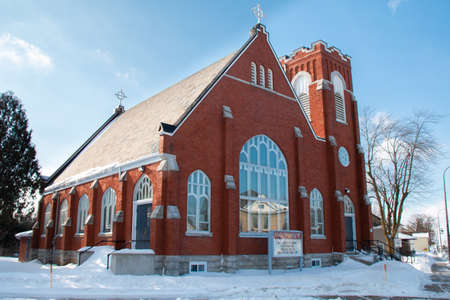 Lucan, Ontario, Canada - February 6 2021: Wide angle photo of Holy Trinity Anglican Church shot on a February blue-sky morning in 2021. Icicles hang off the roof and snow carpets the walkway.のeditorial素材