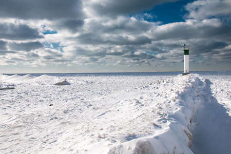 Grand Bend, Ontario, Canada - At the edge of the Grand Bend Pier, the lighthouse looks out onto a thick carpet of ice amid a polar vortex and cold snap in the region, 2021.の写真素材