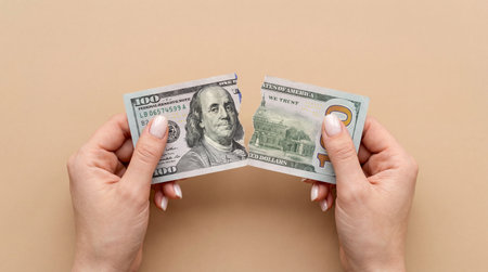 Woman's hands holding a hundred dollar bill on a beige backgroundの素材