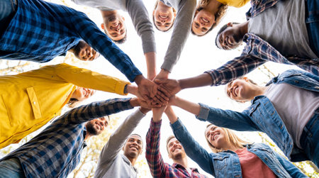 Low angle view of group of young people holding hands in circle outdoorsの素材