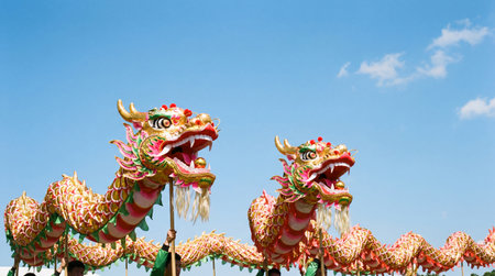 a vibrant image showcasing two chinese dragon puppets with intricate scales against a clear blue sky, capturing the essence of cultural celebrationsの素材