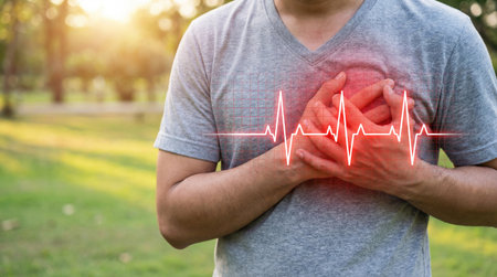 a man clutches his chest with a red heartbeat line overlay, possibly indicating a heart attack or cardiac arrest in a park settingの素材