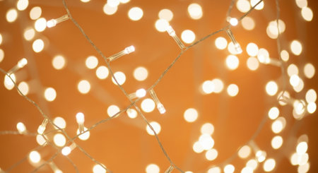 Close-up of many small, bright, glowing lights against an orange background, creating a festive atmosphere.の素材