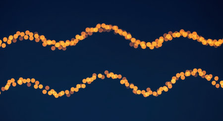 Two wavy lines of golden lights create a festive and abstract pattern against a dark blue backdrop, evoking a sense of warmth and celebration.の素材