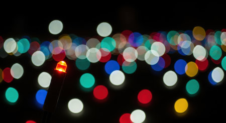 A captivating display of colorful bokeh lights, out of focus, against a deep black background, evoking a sense of celebration and abstract beauty.の素材