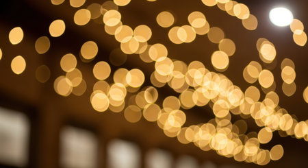 Defocused golden lights create a magical and warm atmosphere. This abstract image features circular bokeh patterns against a dark backdrop, perfect for festive or elegant designs.の素材