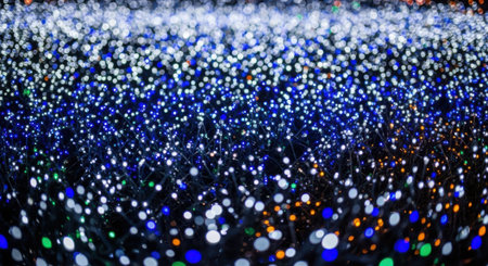 A bokeh effect of numerous small, out-of-focus lights in shades of blue and white, creating a dreamy, abstract background.の素材