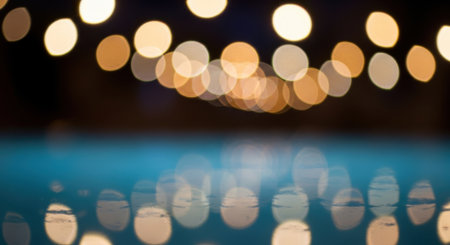 Blurred bokeh lights create a dreamy, abstract effect, reflecting on a dark water surface, evoking a sense of mystery and tranquility.の素材