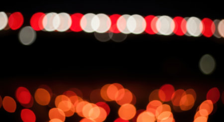 A captivating display of out-of-focus lights, featuring a mix of red and white circular bokeh effects against a deep black background, evoking a sense of celebration and mystery.の素材