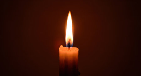 Close-up shot of a lit candle with a bright flame against a dark background, creating a warm and intimate atmosphere.の素材