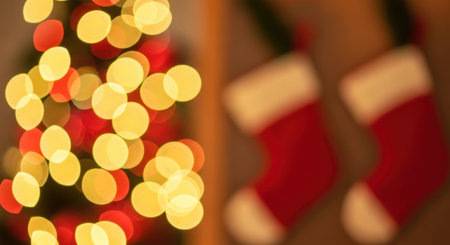 A festive and warm holiday scene featuring out-of-focus Christmas tree lights in red and yellow, alongside two blurred red Christmas stockings, evoking a cozy winter atmosphere.の素材