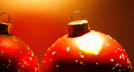 A detailed close-up shot of two shiny red Christmas ornaments, adorned with white speckles, illuminated by warm light.の素材