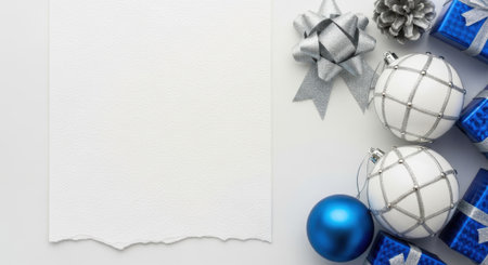Overhead shot of Christmas decorations including ornaments, gifts, and bows arranged around a blank sheet of paper, perfect for adding a holiday message.の素材