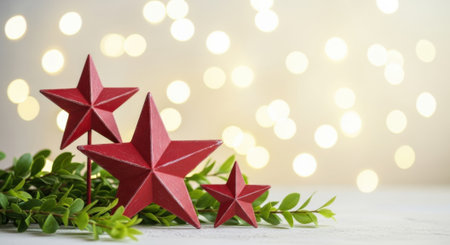 A festive arrangement of red star ornaments nestled among green foliage, set against a soft bokeh background, creating a warm and inviting holiday atmosphere.の素材