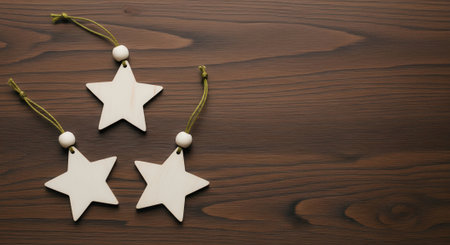 Top view of three rustic white star shaped Christmas decorations with twine hangers lying on a dark brown wooden table with copy space for text.の素材