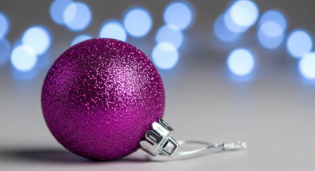A close-up of a purple Christmas ornament with a blurred background of bokeh lights, creating a festive and celebratory atmosphere.の素材