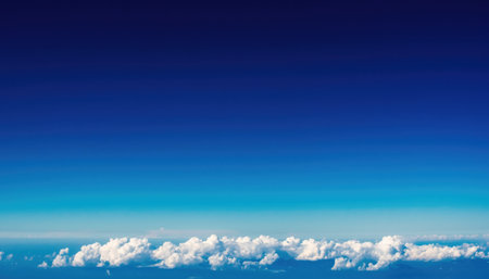 An aerial view of a clear blue sky with a distinct layer of white clouds below.の素材
