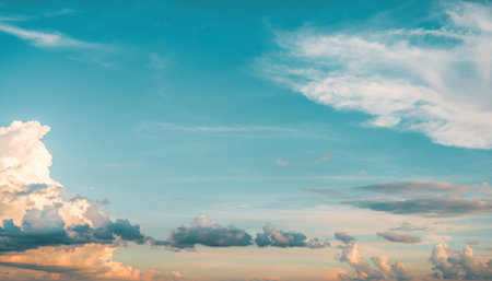 A breathtaking view of a wide sky filled with dynamic clouds, painted with the warm hues of a setting sun.の素材