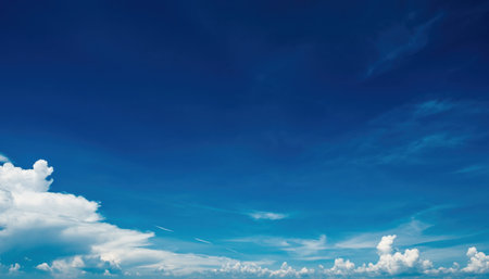 A beautiful expanse of deep blue sky dotted with soft, white cumulus clouds, suggesting a clear and bright day.の素材