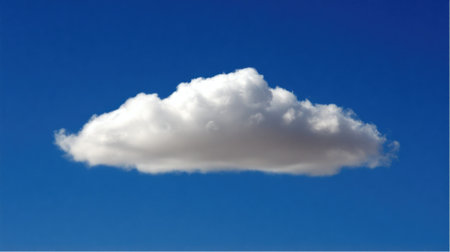 A solitary cumulus cloud, bright white and well-defined, drifts against a deep blue sky.の素材