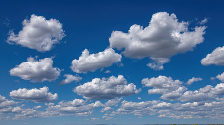 A beautiful expanse of blue sky filled with numerous fluffy white cumulus clouds, suggesting a clear and pleasant day.の素材