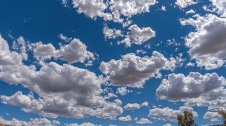 A bright blue sky filled with numerous fluffy white cumulus clouds, suggesting a clear and pleasant day.の素材