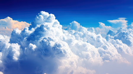 A breathtaking aerial view of voluminous cumulus clouds bathed in sunlight, set against a vibrant, deep blue sky.の素材